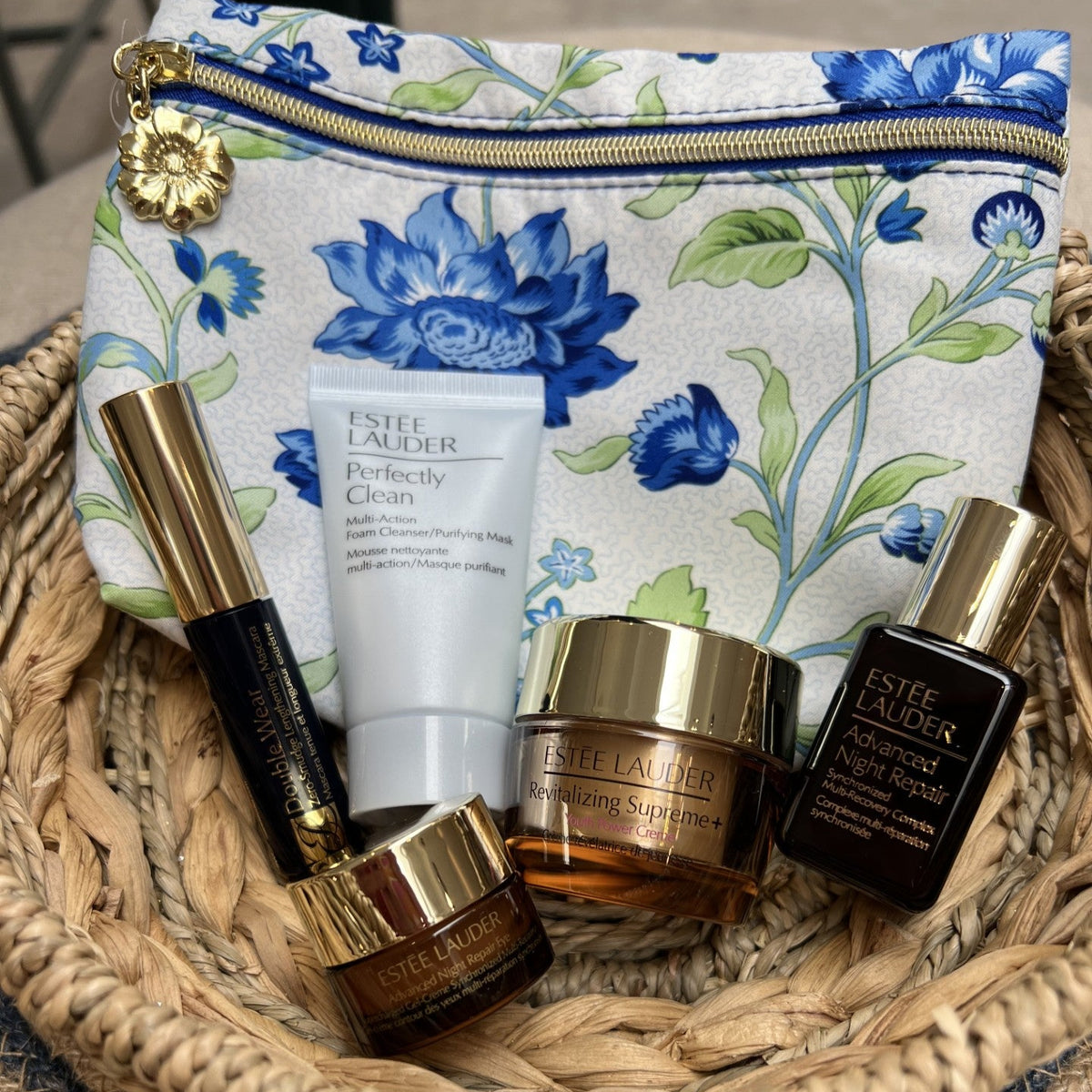Estée Lauder skincare products on a woven mat with a floral pouch in the background